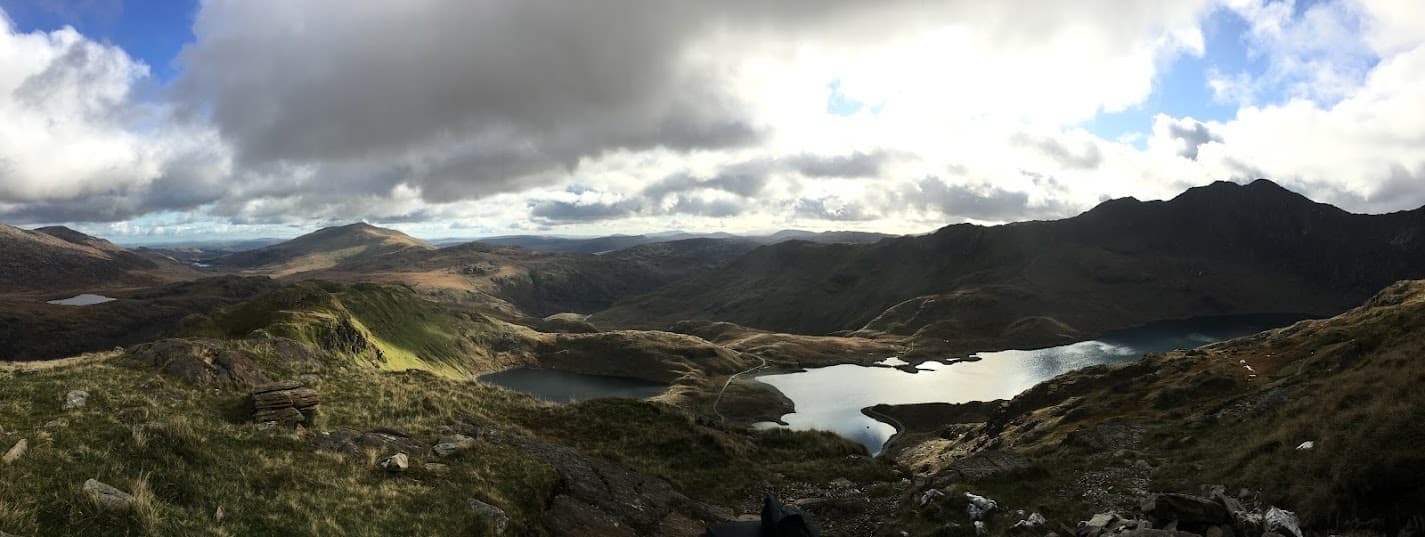 A panoramic view over mountain lakes and ridgelines from a summit in Wales, on one of Will and Issy's hikes